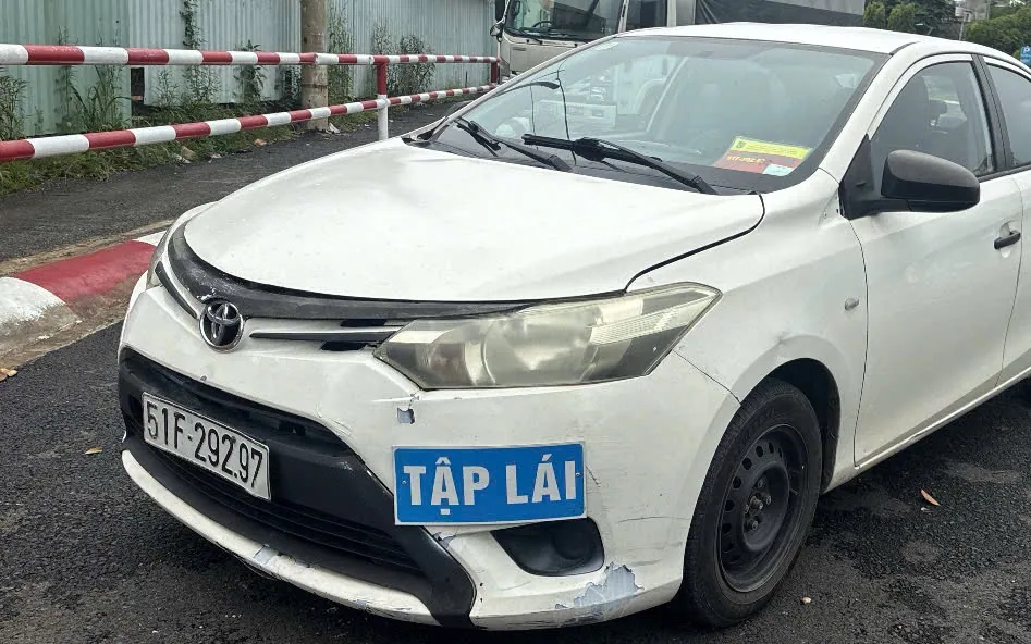Xe con tập lái số sàn gắn biển TẬP LÁI, đỗ tại sân của trung tâm